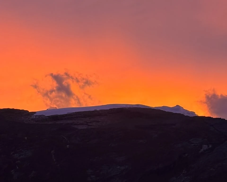 Amanecer sobre el glaciar de la Sierra Nevada del Cocuy, con el cielo naranja detrás de la cresta nevada