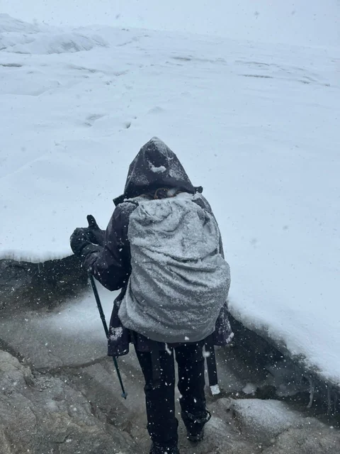 Un caminante subiendo al Ritacuba con la mochila cubierta de nieve, durante una nevada