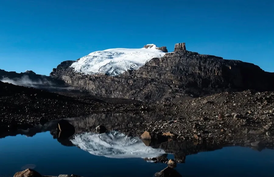 El Pan de Azúcar nevado y la torre de roca del Púlpito del Diablo reflejados en una laguna del Parque Nacional Natural El Cocuy